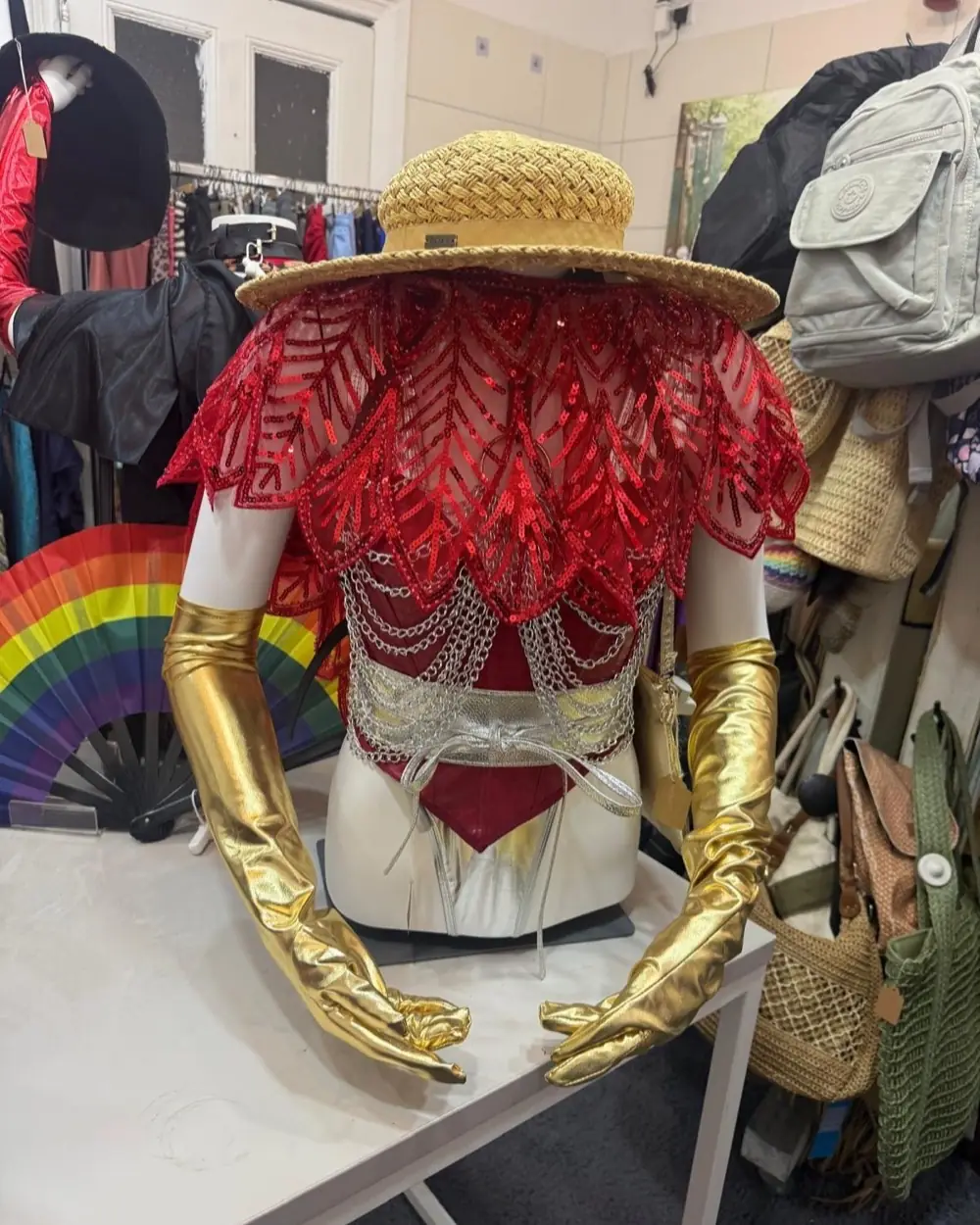 Rotes Pailletten-Cape, Goldhandschuhe und Strohhut auf der Büste bei CHAoS iN fORm